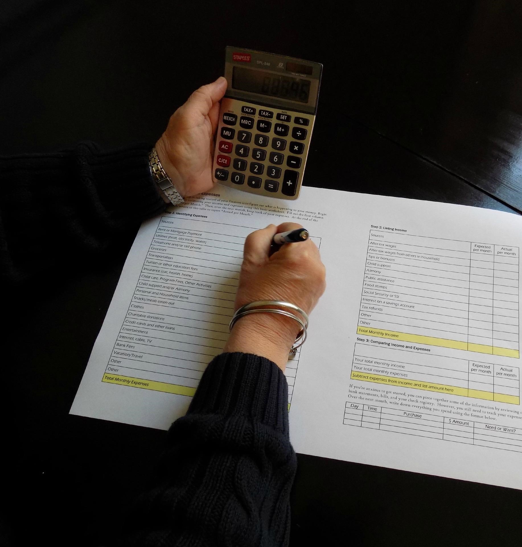 Женщина вносит цифры с калькулятора в документ